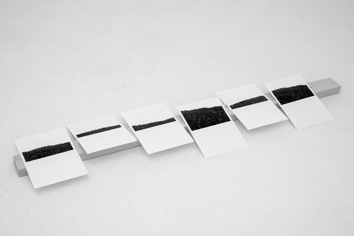 Six petits socles blancs alignés au sol, chacun portant une matière noire granuleuse.